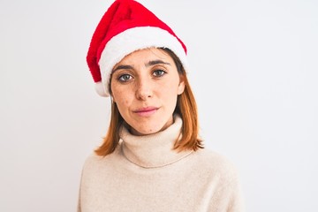 Beautiful redhead woman wearing christmas hat over isolated background with a confident expression on smart face thinking serious