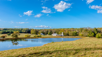 Pond with a farm with a barn and silo in the background