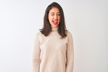 Beautiful chinese woman wearing turtleneck sweater standing over isolated white background winking looking at the camera with sexy expression, cheerful and happy face.