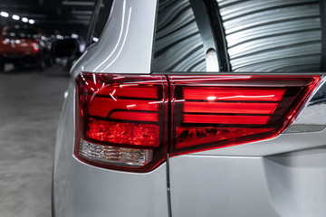  Close up detail on one of the LED red taillight modern silver crossover car. Exterior detail automobile..