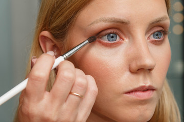 Fototapeta premium The process of creating makeup. Makeup artist working with a brush on the face of the model.
