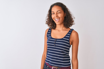 Obraz premium Young brazilian woman wearing striped t-shirt standing over isolated white background winking looking at the camera with sexy expression, cheerful and happy face.