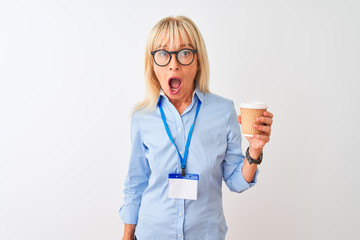 Businesswoman wearing glasses and id card drinking coffee over isolated white background scared in shock with a surprise face, afraid and excited with fear expression