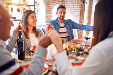 Beautiful family meeting smiling happy and confident. Praying taking hands before eating roasted turkey celebrating Christmas at home