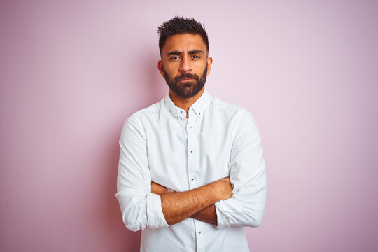 Young indian businessman wearing elegant shirt standing over isolated pink background skeptic and nervous, disapproving expression on face with crossed arms. Negative person.