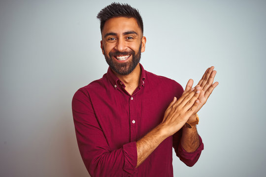 Young indian man wearing red elegant shirt standing over isolated grey background clapping and applauding happy and joyful, smiling proud hands together