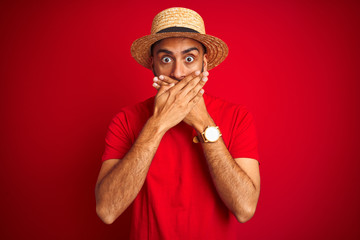 Young handsome indian man wearing t-shirt and hat over isolated red background shocked covering mouth with hands for mistake. Secret concept.