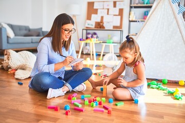 Young therapist woman speaking and treating child, counselor and behaviour correction at pedagogue payroom taking notes on clipboard