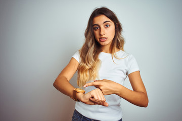 Young beautiful woman wearing casual white t-shirt over isolated background In hurry pointing to watch time, impatience, upset and angry for deadline delay