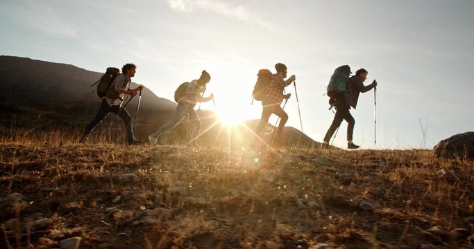 Four young people on hike adventure - Group of students trekking in mountains together, having a vacation - friendship, travel destination concept 4k footage