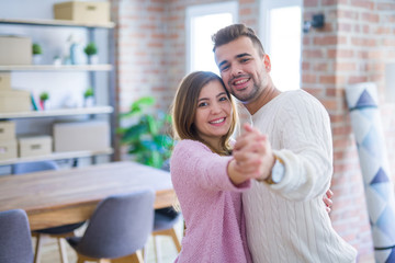 Young beautiful couple in love celebrating dancing moving to a new home, smiling very happy for new apartment