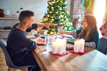 Young beautiful couple smiling happy and confident. Eating food celebrating christmas at home