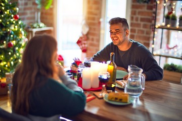 Young beautiful couple smiling happy and confident. Eating food celebrating christmas at home