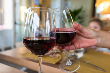 two glasses of red wine ,a human hand hlding one of the glasses 