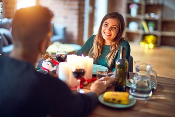 Young beautiful couple smiling happy and confident. Eating food celebrating christmas at home
