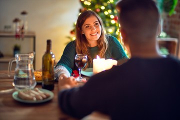 Young beautiful couple smiling happy and confident. Eating food celebrating christmas at home
