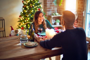 Young beautiful couple smiling happy and confident. Eating food celebrating christmas at home