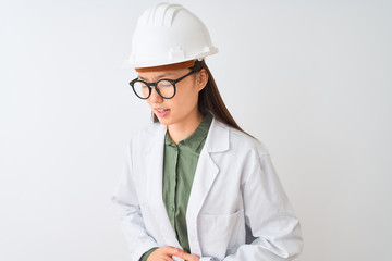 Young chinese engineer woman wearing coat helmet glasses over isolated white background with hand on stomach because indigestion, painful illness feeling unwell. Ache concept.