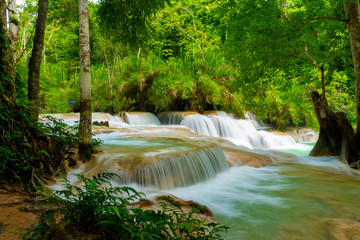 Tat Kuang Si Falls near to popular travel destination Luang Prabang in Laos. Three level waterfall with turquoise blue pools surrounded with lush green tropical jungle.