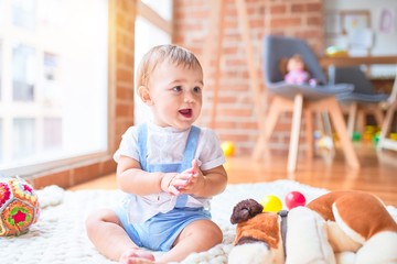 Beautiful toddler sitting on the blanket around lots of toys at kindergarten