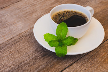 cup of coffee and beans with mint leaf isolated on wood  table background