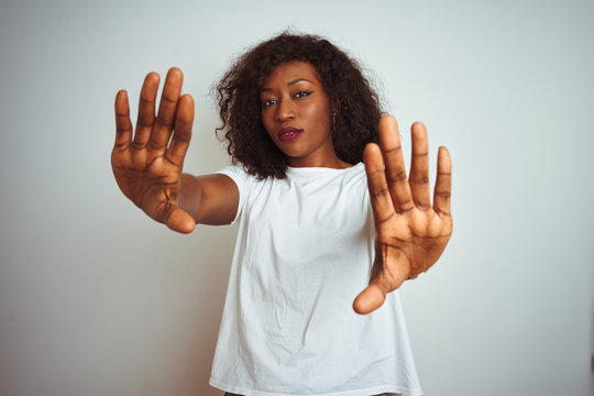 Young african american woman wearing t-shirt standing over isolated white background doing frame using hands palms and fingers, camera perspective