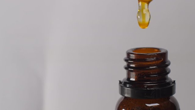Close up of herbal oil infusion drops from bottle using pipette.