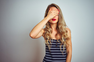Fototapeta premium Young beautiful woman wearing stripes t-shirt standing over white isolated background covering eyes with hand, looking serious and sad. Sightless, hiding and rejection concept