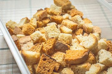 Baked sliced white bread rusks in white container on kitchen table.