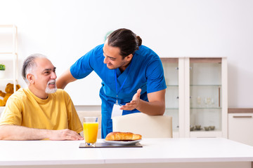 Young male doctor visiting old patient at home