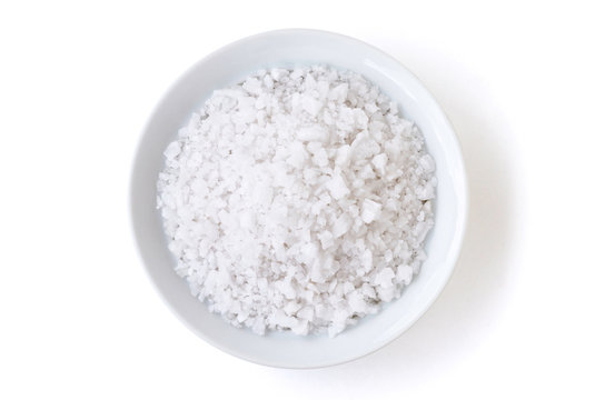 Closeup coarse or rock natural sea salt in brown bowl isolated on white background. Clipping path. Top view.	