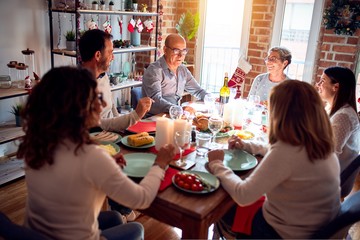 Family and friends dining at home celebrating christmas eve with traditional food and decoration, celebration of festive winter time