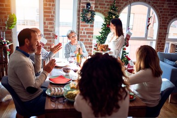 Family and friends dining at home celebrating christmas eve with traditional food and decoration, showing proud turkey cooking