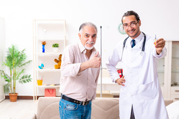 Young male doctor visiting old patient at home