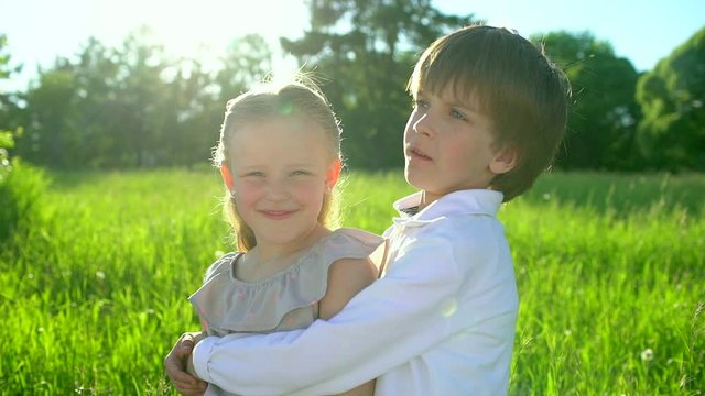 Little cute boy and pretty girl hugging and kissing each other on summer day. Brother and little sister cuddling. Happy family outdoors. children having fun at sunset. childhood first love, friendship
