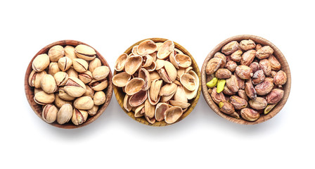 Bowls with tasty pistachio nuts isolated on white