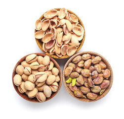 Bowls with tasty pistachio nuts isolated on white