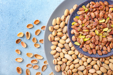 Plate with tasty pistachio nuts on table