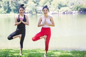 Two Asian women are practicing and doing morning yoga for good health. happily