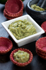 Closeup of guacamole dip sauce with vegetable tartlets, vertical shot, selective focus