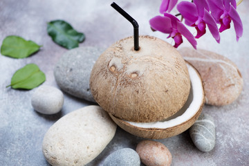 Fototapeta na wymiar Natural coconut drink, studio shot over beige stone background with pebbles