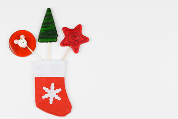Red and green lollipops in red sock on white background. Invitation, christmas celebration