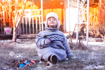 little boy in a hat with earflaps and a warm sweater outdoors, cool frosty morning, snow