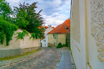 Fototapeta na wymiar Narrow, empty, cozy street of an old European city with houses and a wall