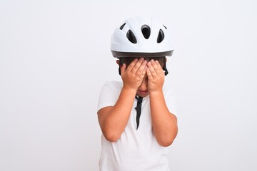 Beautiful kid boy wearing bike security helmet standing over isolated white background suffering from headache desperate and stressed because pain and migraine. Hands on head.
