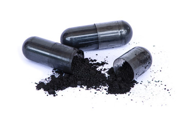Closeup activated charcoal capsules with powder isolated on white background.