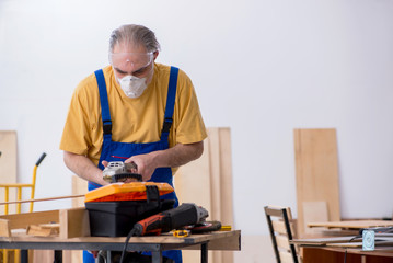Old male carpenter working in workshop
