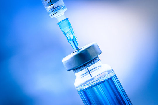 Close up of flu and measles vaccine vials with syringe injection, medicine and drug concept