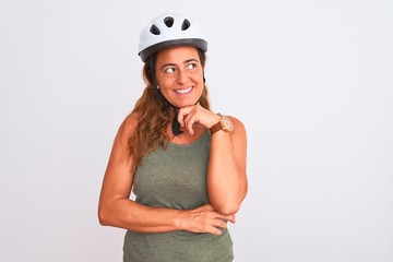 Middle age mature cyclist woman wearing safety helmet over isolated background with hand on chin thinking about question, pensive expression. Smiling and thoughtful face. Doubt concept.