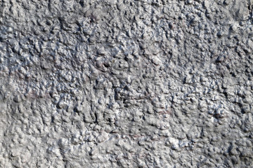 Texture of a wall made of crushed stone plastered with cement painted in silver